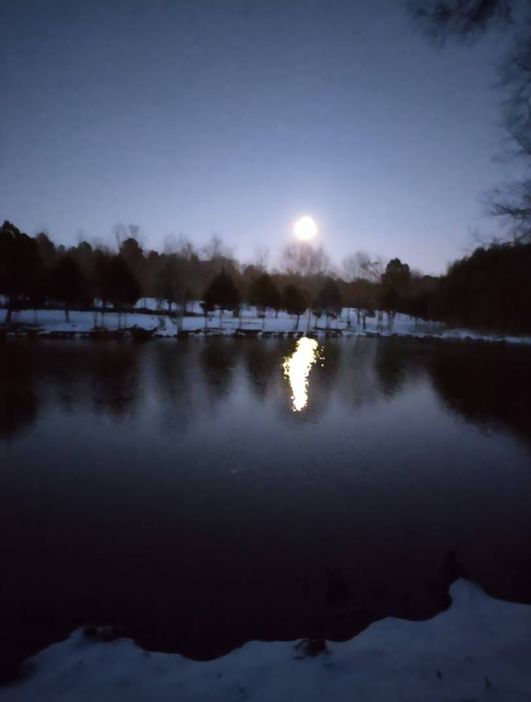 Full moon rising over the snow-covered lake